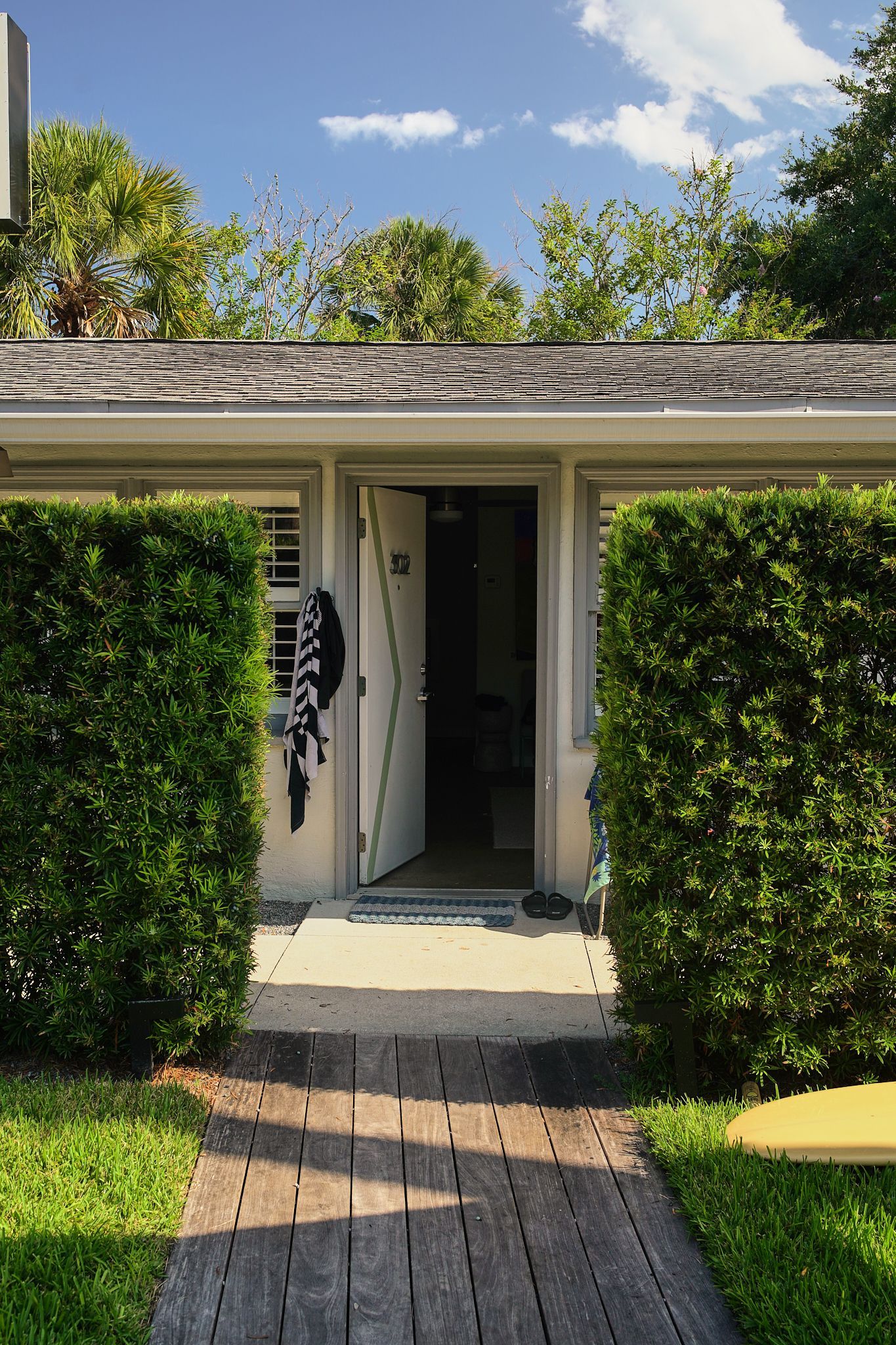 Front walkway leading to a house entrance framed by trimmed hedges and a paved path