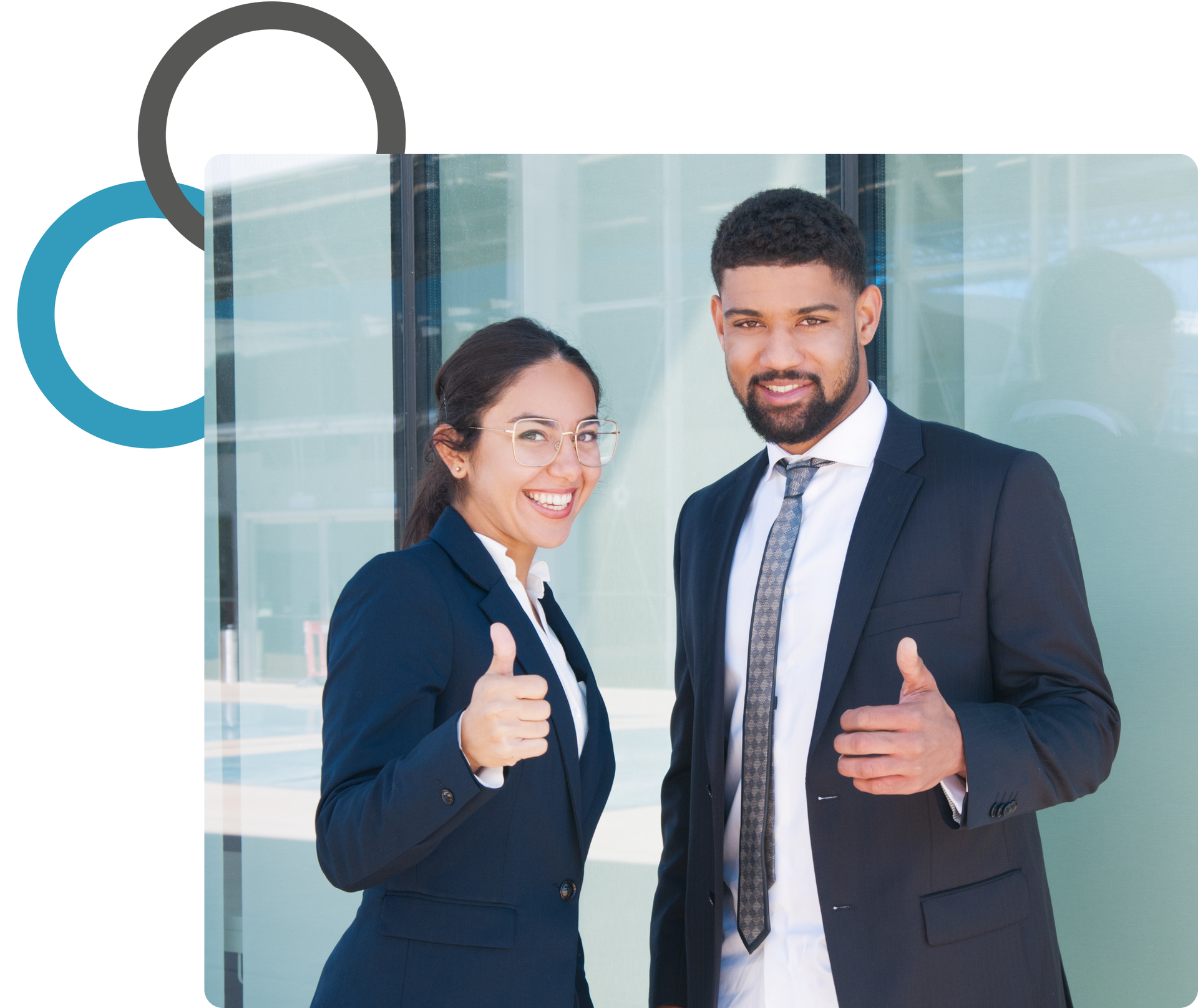 Two business professionals smiling and giving thumbs up in front of a glass office wall