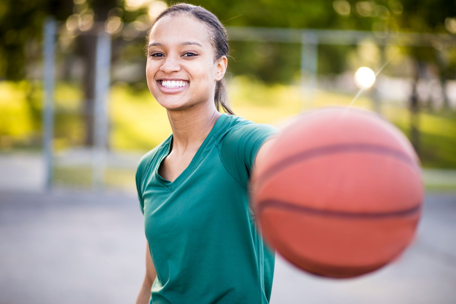 A young woman is holding a basketball in her hand and smiling.