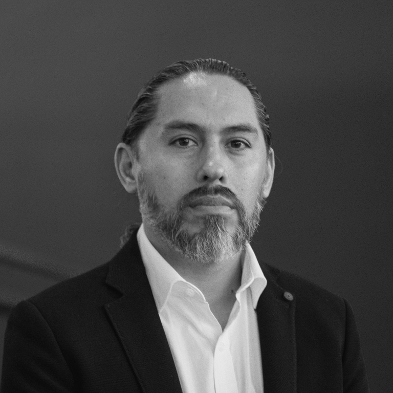 Un hombre con barba viste traje y camisa blanca.