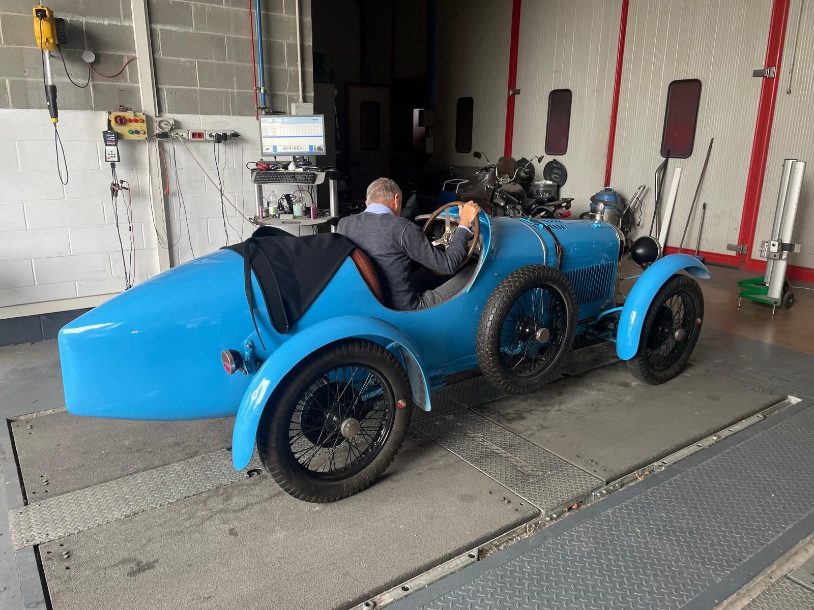 Auto d'epoca blu con autista a bordo, in un garage.