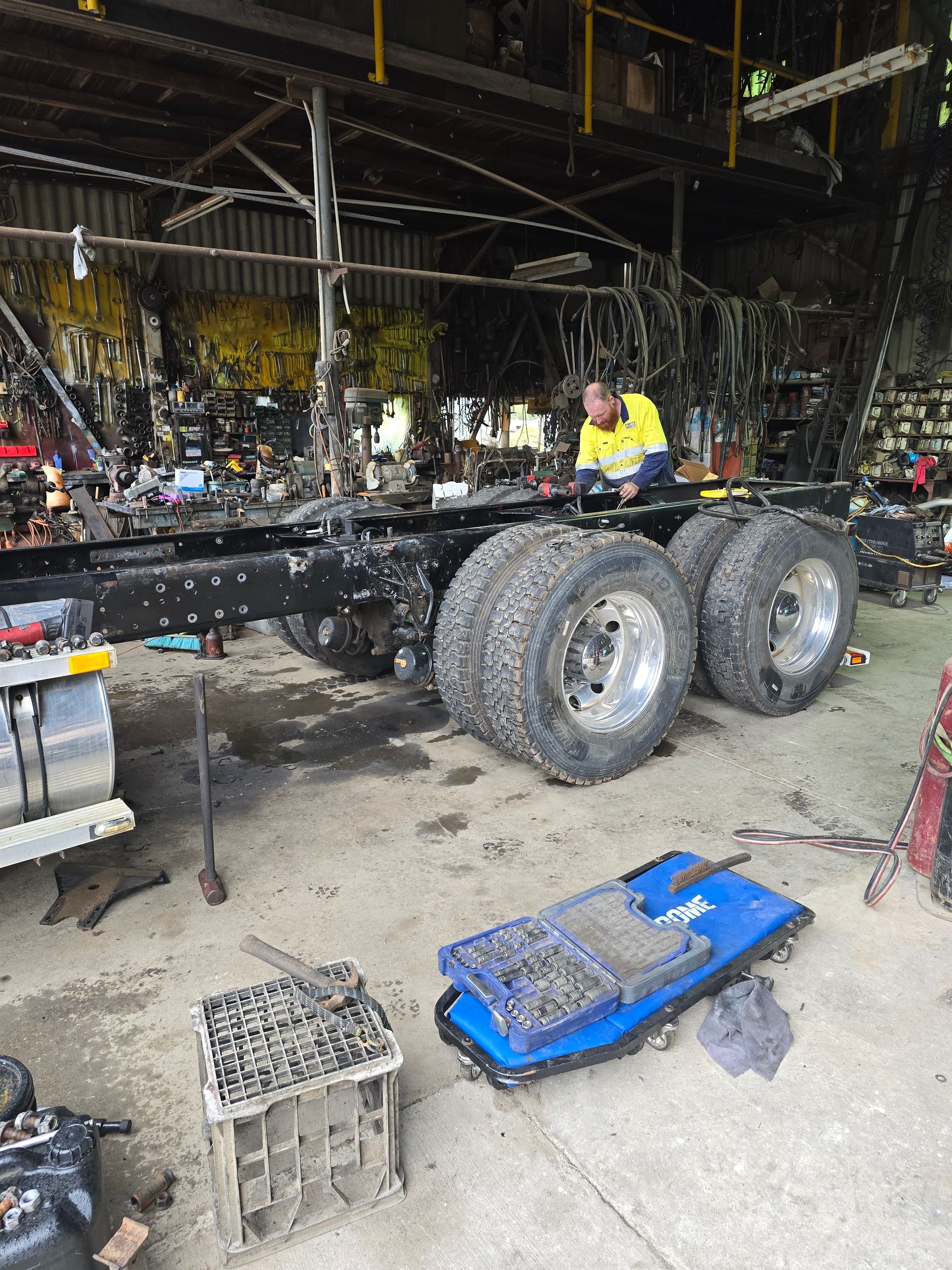A Mechanic Works on The Exposed Chassis of A Large Truck Inside a Repair Garage — Banana Coast Heavy Diesel in Kempsey, NSW