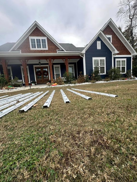 House exterior with white siding panels laid across the front yard, under construction.
