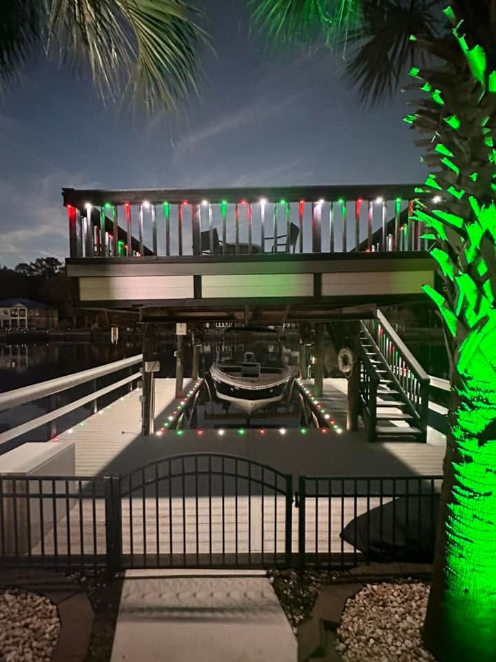 Backyard pool at night with string lights, a raised deck, and a hammock over the water