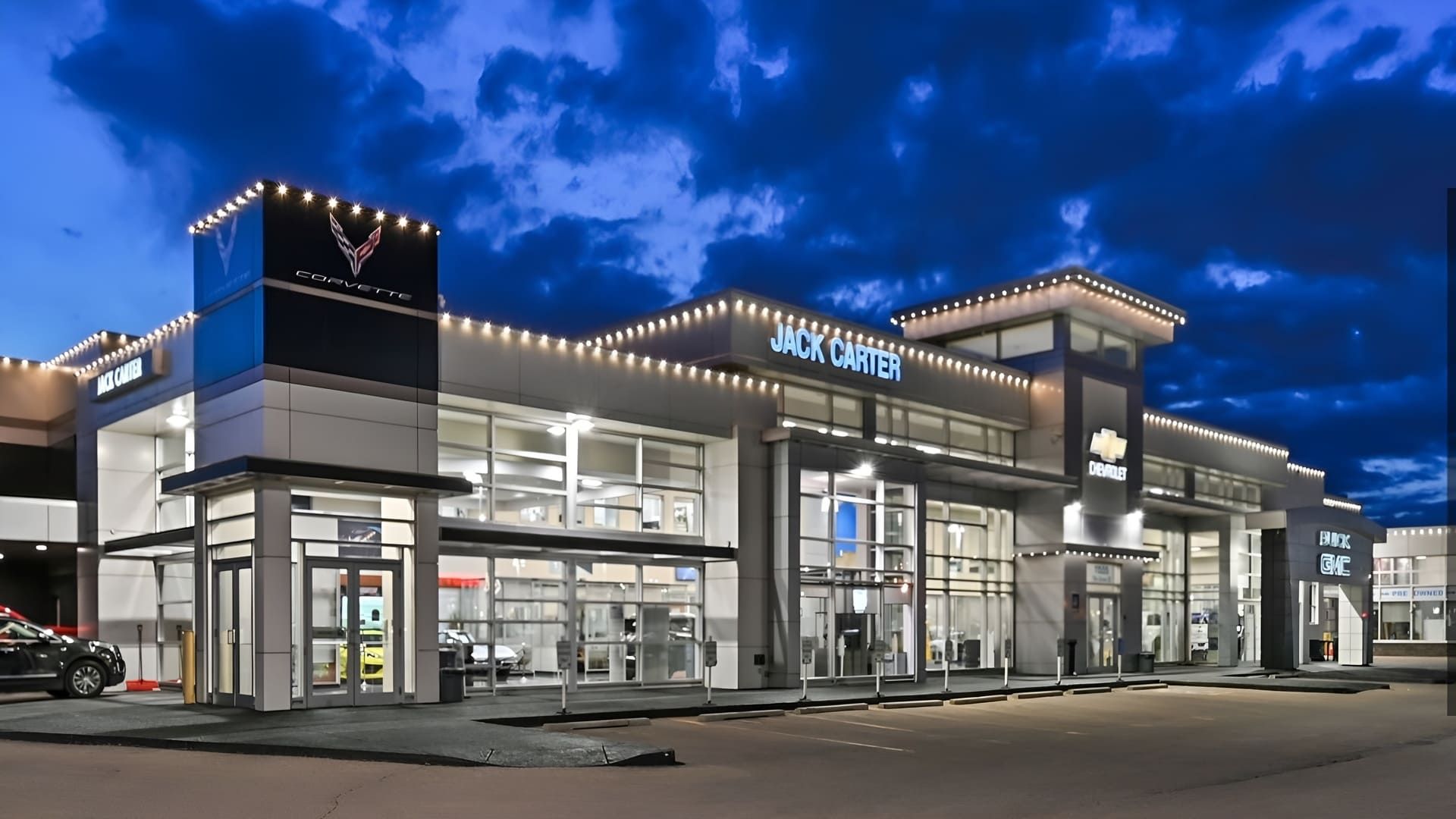 Modern glass storefront at dusk with bright interior lights and blue sky above