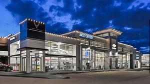 Modern glass storefront at dusk with bright interior lights and blue sky above