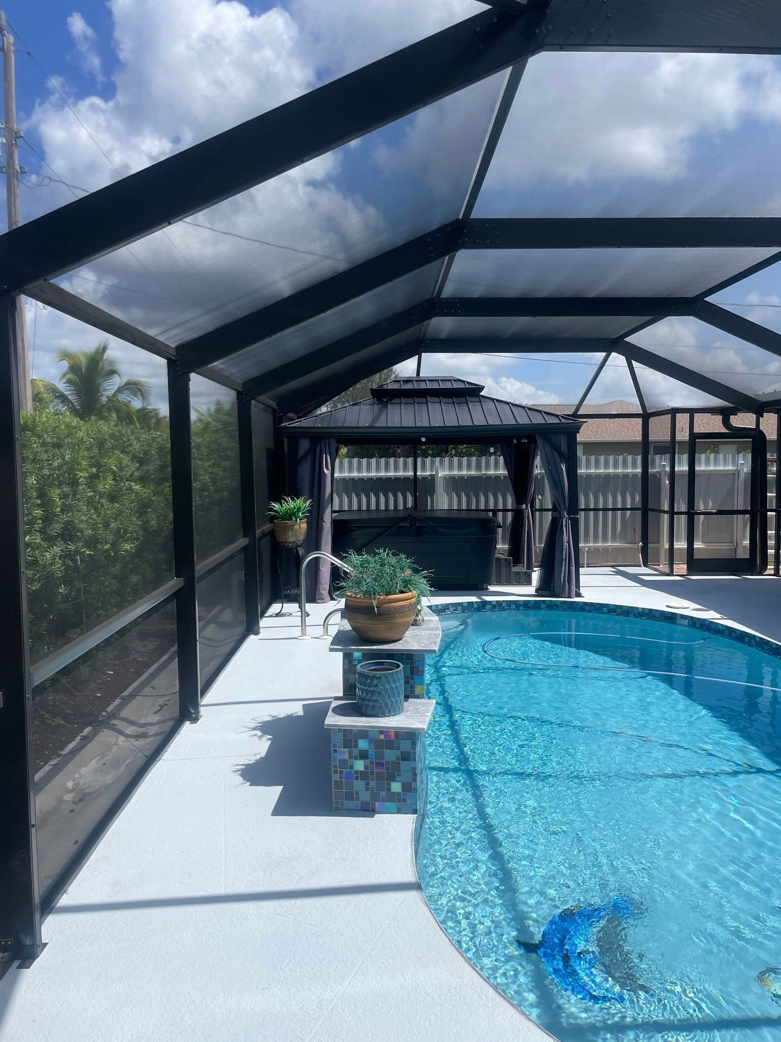 A man is standing on a ladder cleaning a pool screen.