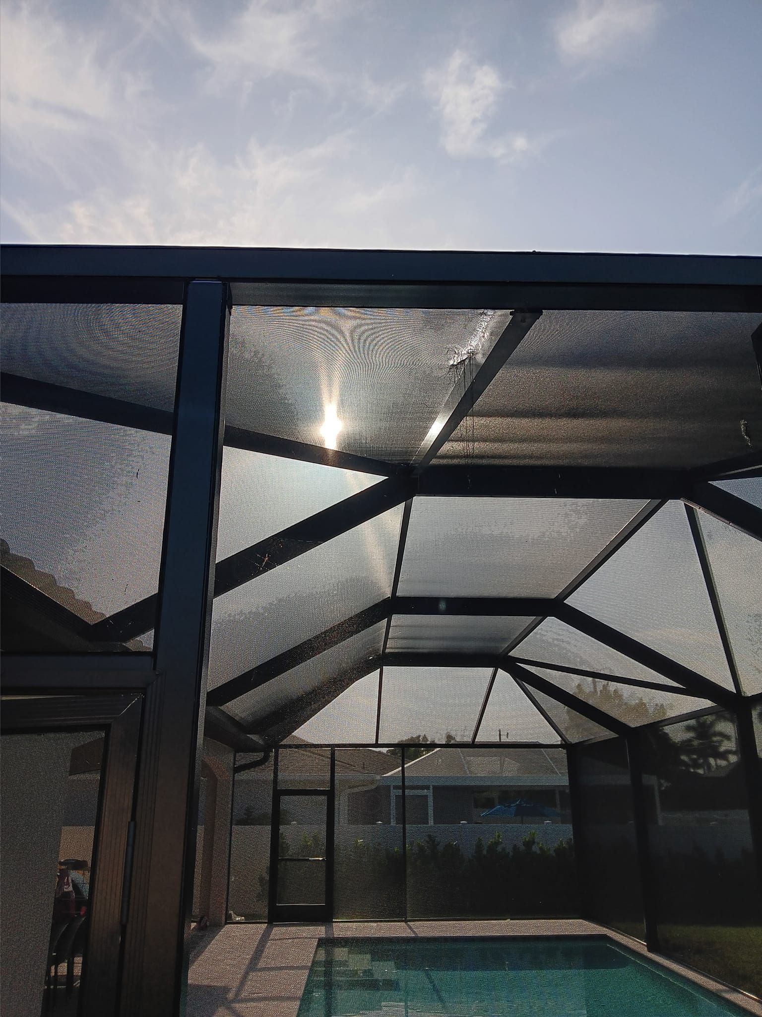 A screened in area with a swimming pool and a bench