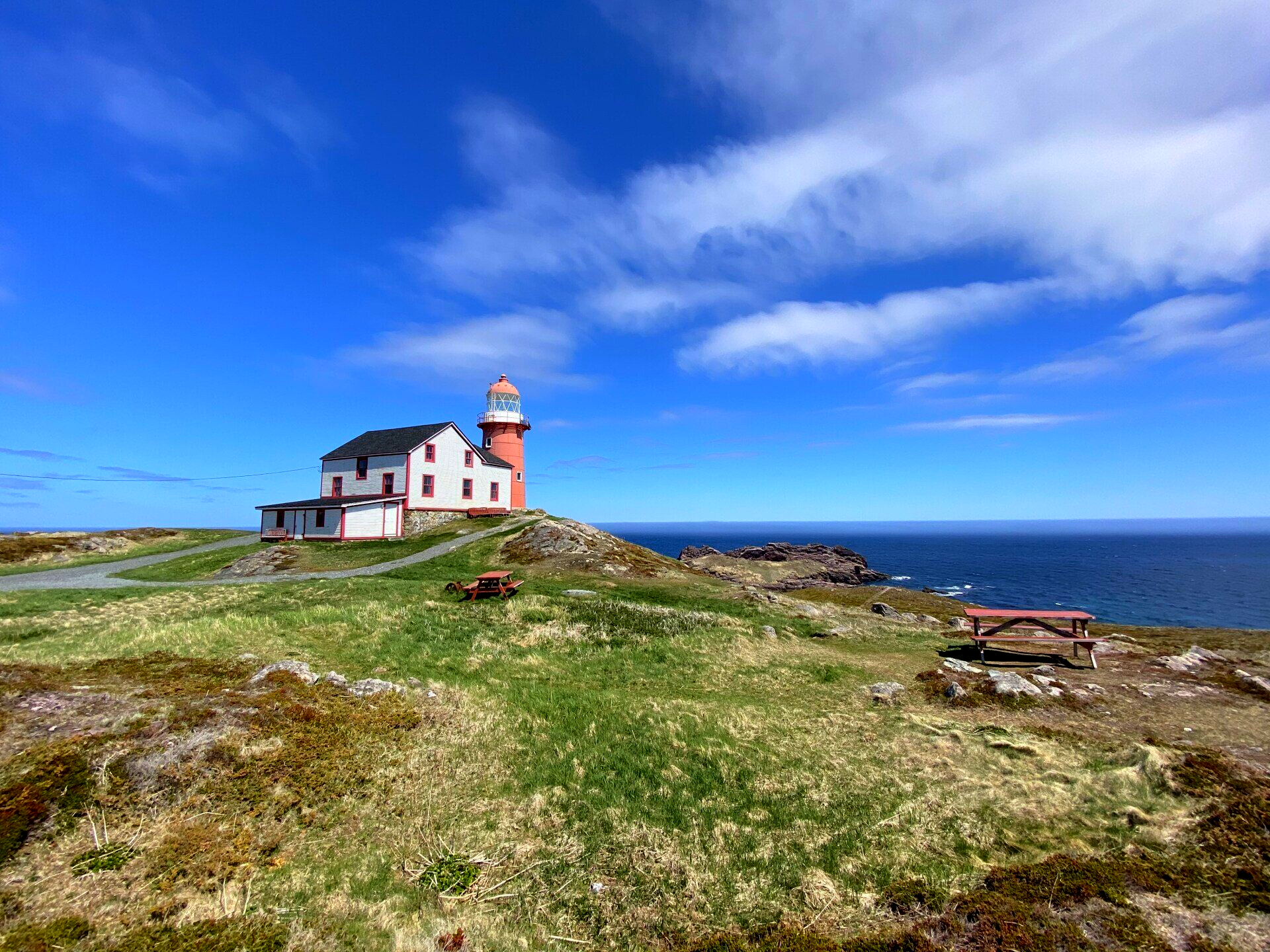 Le phare rouge de Ferryland, avec la maison du gardien blanche et un banc de pique-nique