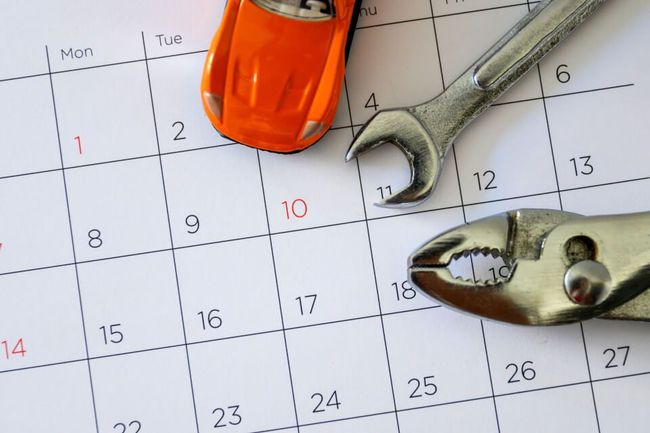 Orange toy car and tools on a calendar, potentially representing car maintenance scheduling.