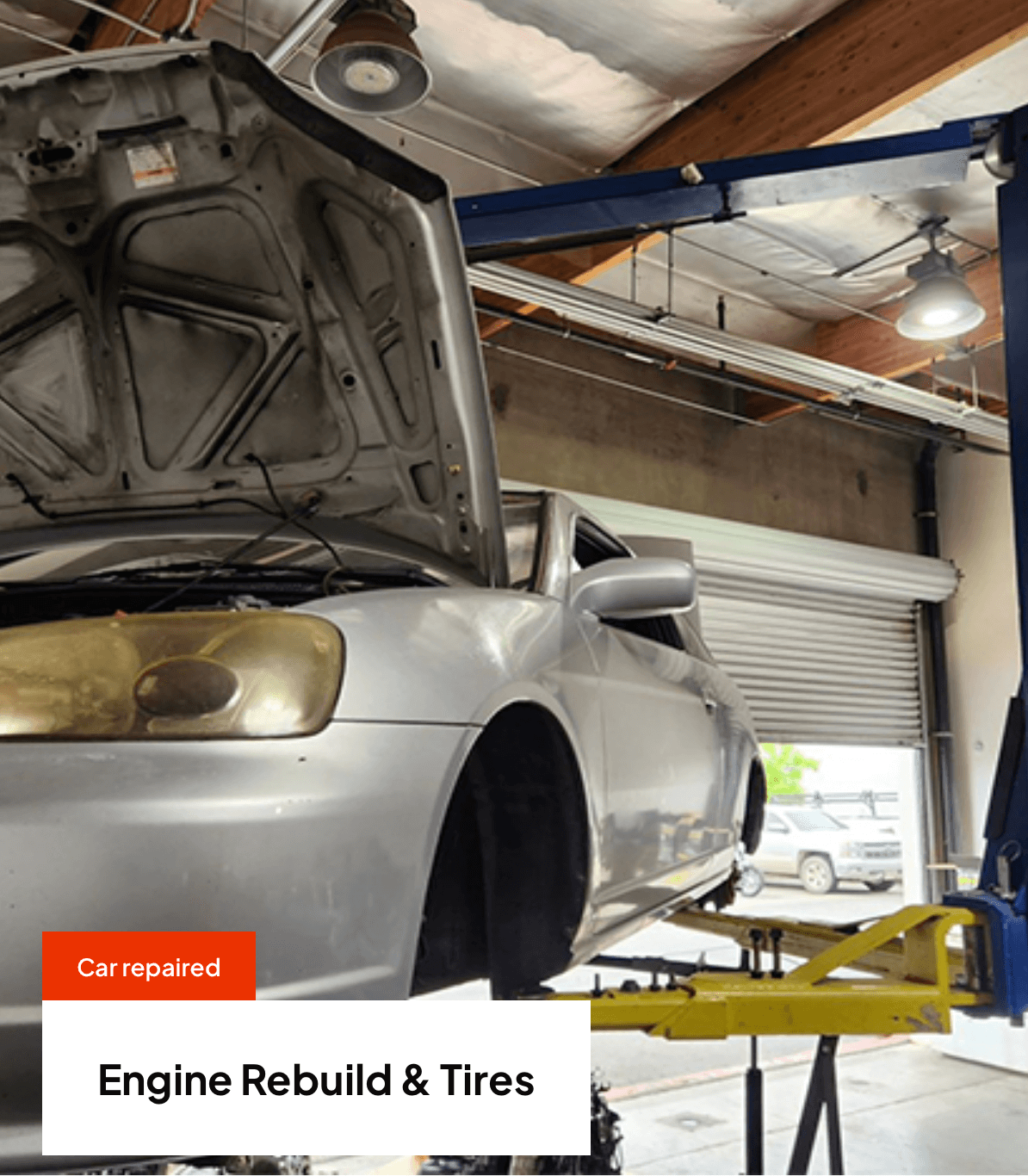 Car on lift, hood open, in repair shop. Engine rebuild and tire services.
