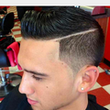 Man with a fade haircut, side part with a line, and a few ear piercings, indoors.