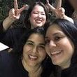 Three smiling women, one making peace signs behind the others.
