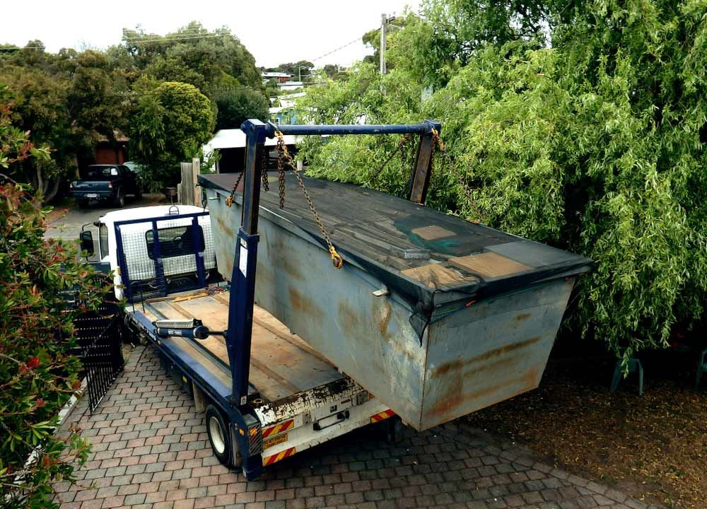 A Dumpster is Sitting on Top of a Tow Truck — Truck Training and Assessments In Umina Beach, NSW