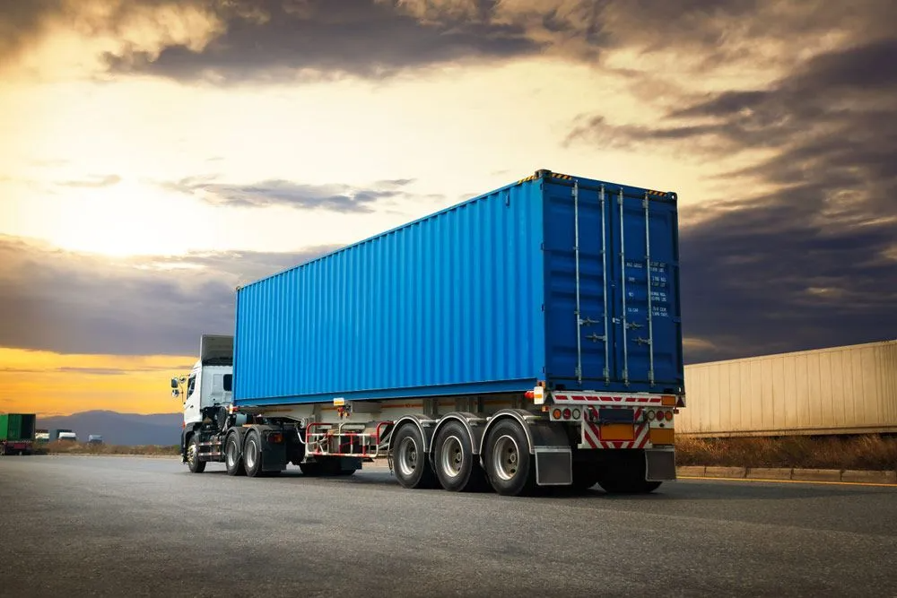 A Blue Container Truck is Driving Down a Road — Truck Training and Assessments In Umina Beach, NSW