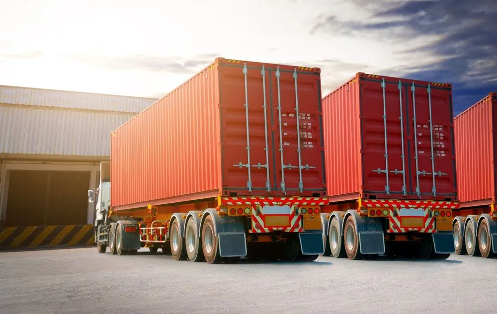 A Row of Red Shipping Containers Are Parked in Front of a Warehouse — Truck Training and Assessments In Umina Beach, NSW