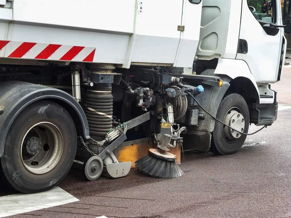 A Street Sweeper is Cleaning the Road With a Brush — Truck Training and Assessments In Umina Beach, NSW