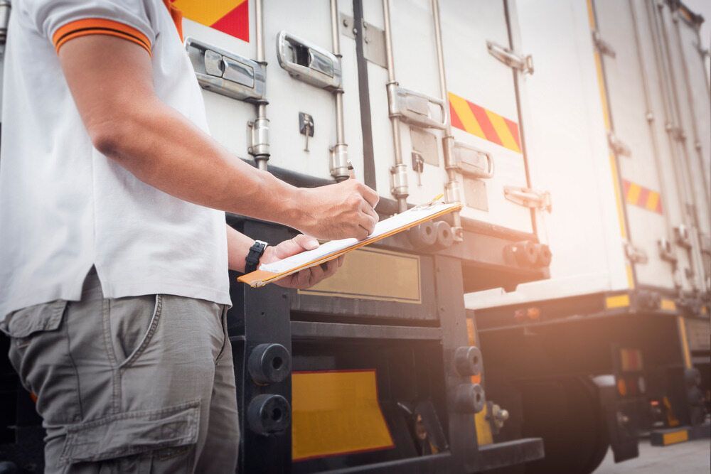 A Man is Standing Next to a Truck Holding a Clipboard — Truck Training and Assessments In Umina Beach, NSW