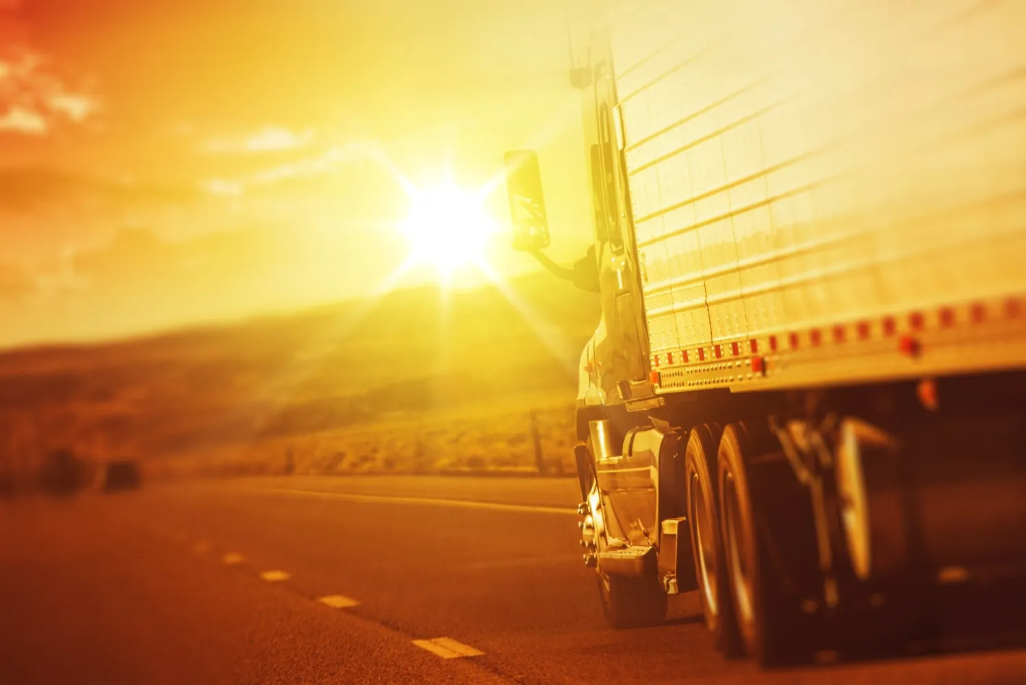 A Semi Truck is Driving Down a Highway at Sunset — Truck Training and Assessments In Umina Beach, NSW