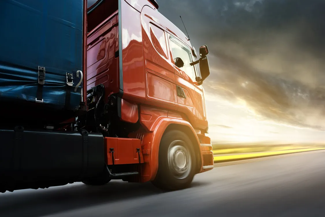 A Red Semi Truck is Driving Down a Highway at Sunset — Truck Training and Assessments In Umina Beach, NSW
