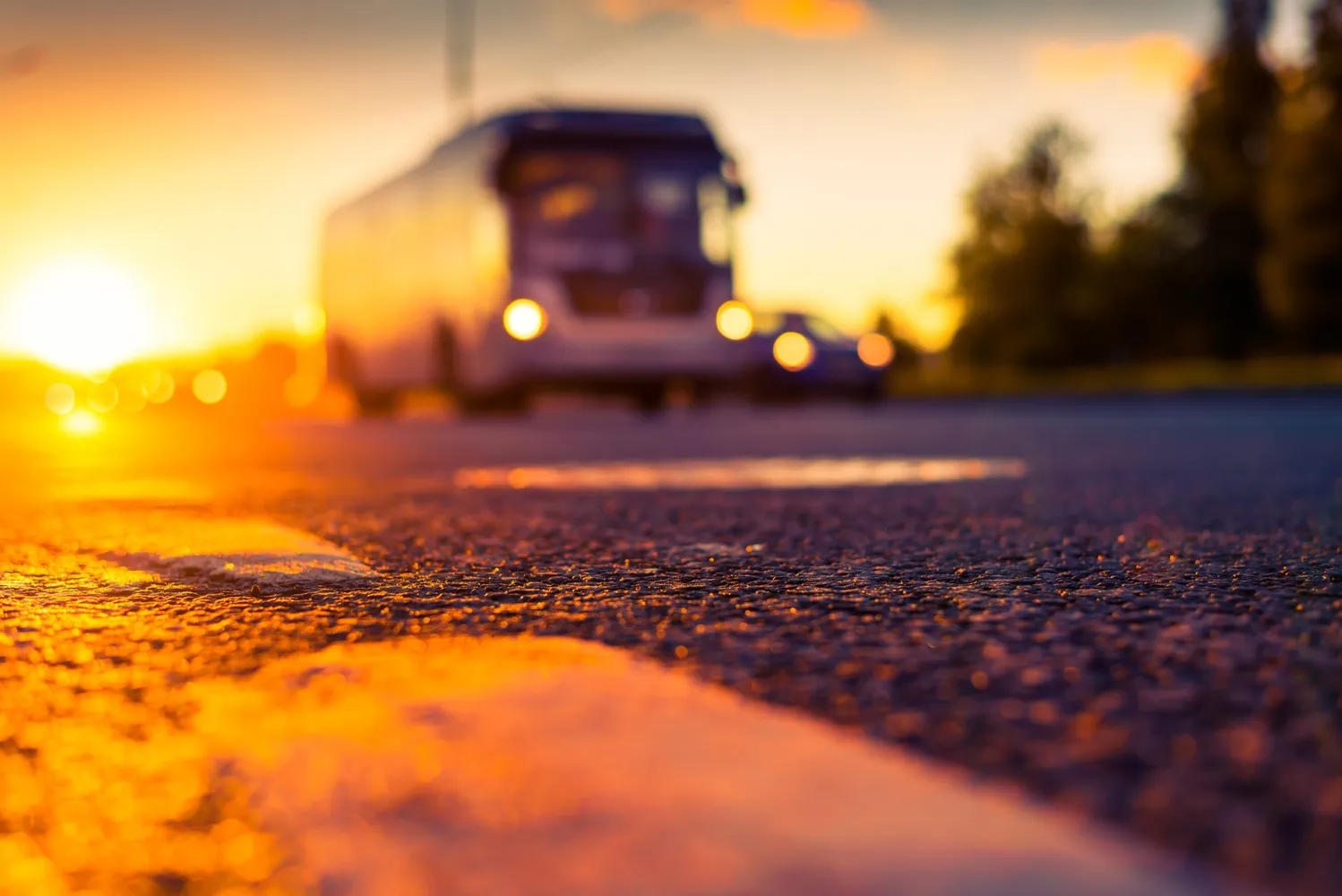 A Bus is Driving Down a Road at Sunset — Truck Training and Assessments In Umina Beach, NSW