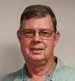 Man wearing glasses, looking at the camera. He is wearing a light green shirt, indoors.