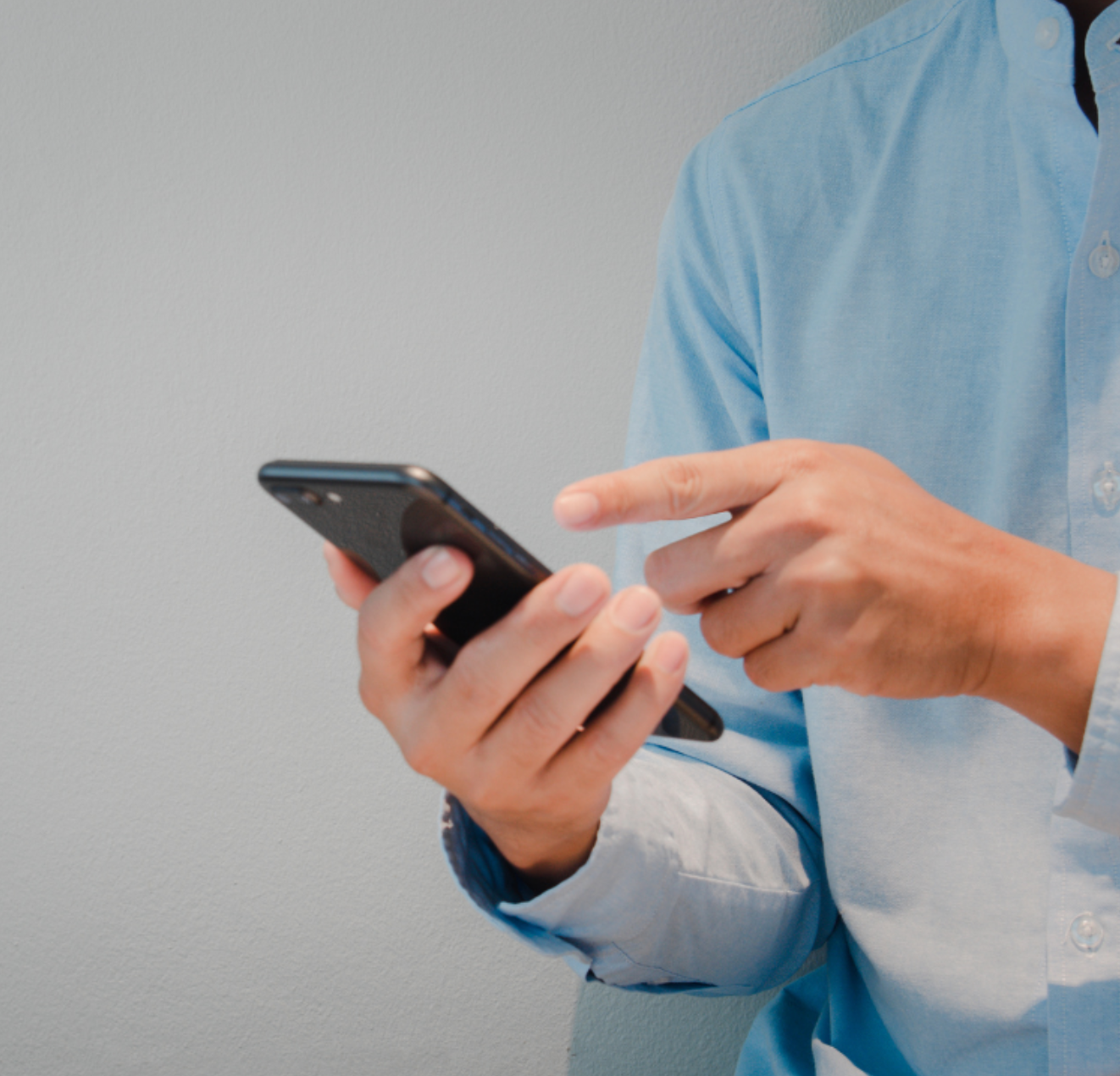 A man in a blue shirt is holding a cell phone
