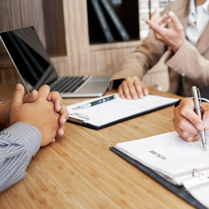 A man and a woman are sitting at a table with papers and a laptop.