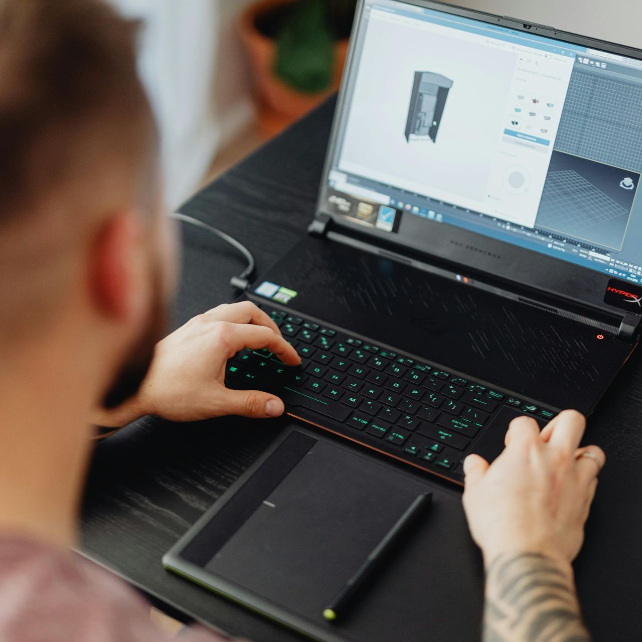 A man is typing on a laptop computer while sitting at a table.