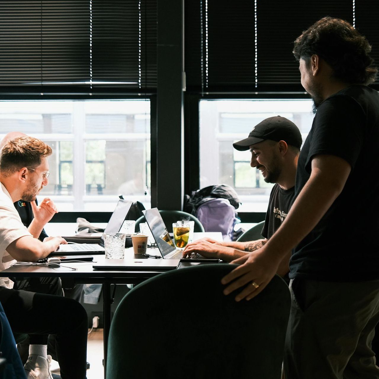 A group of men are sitting at a table with laptops.