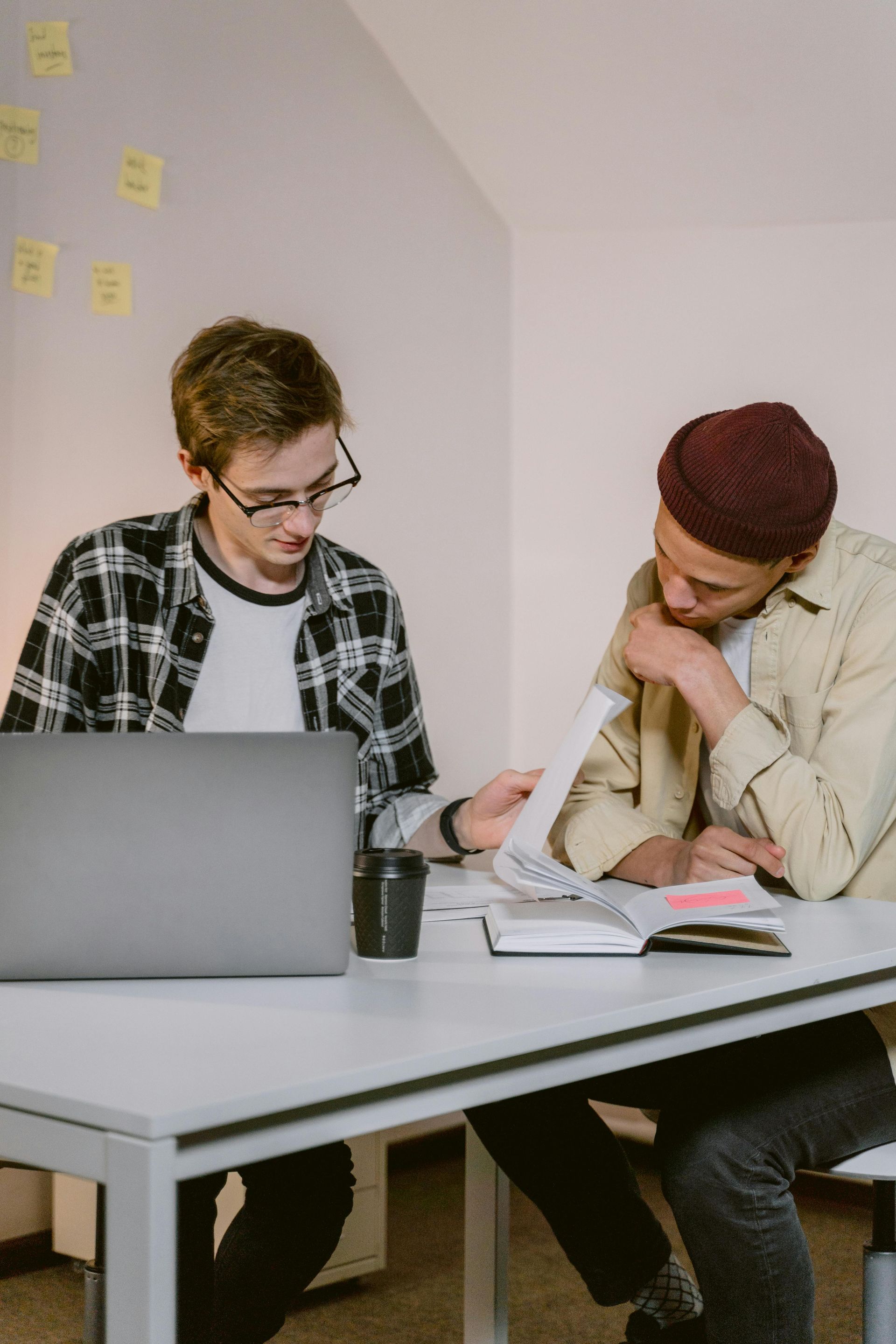 Two men are sitting at a table with a laptop.