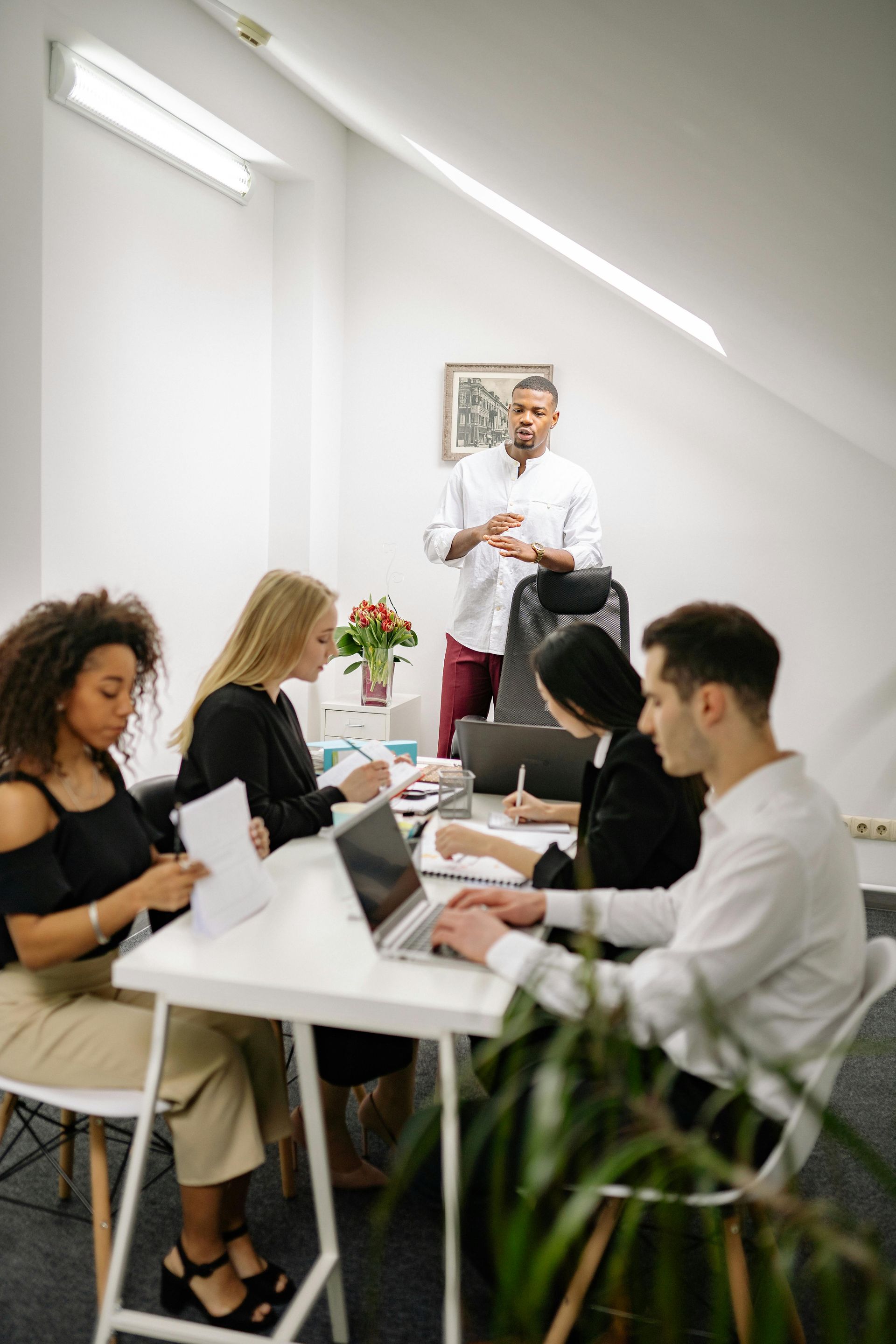 A group of people are sitting around a table in an office having a meeting.