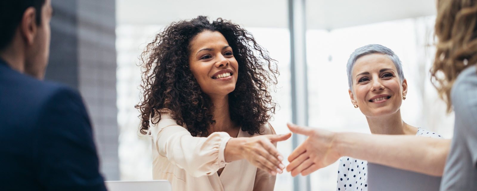 A woman is shaking hands with a man in an office.