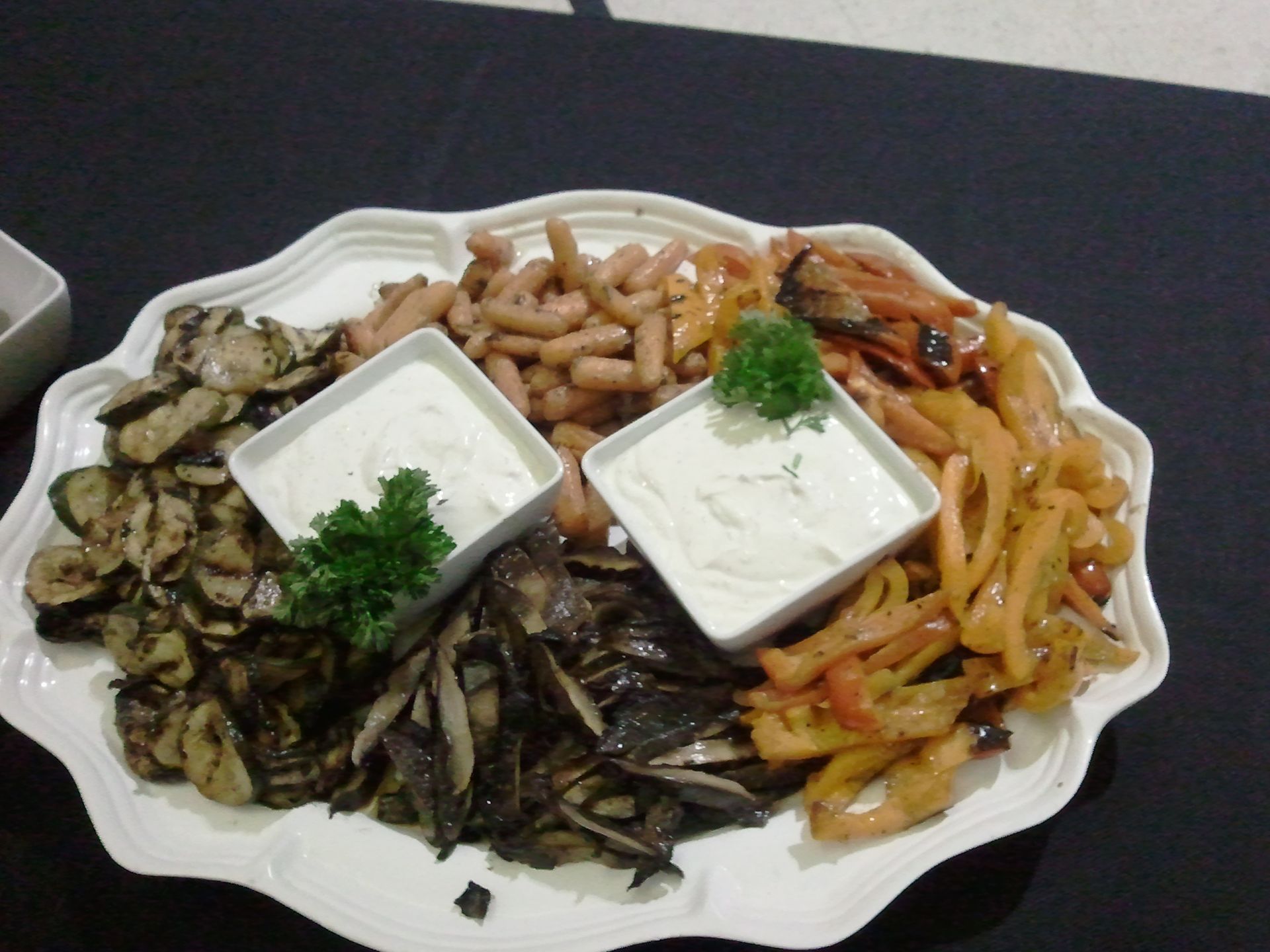 Platter of assorted appetizers with dips, olives, and vegetables on a white serving tray