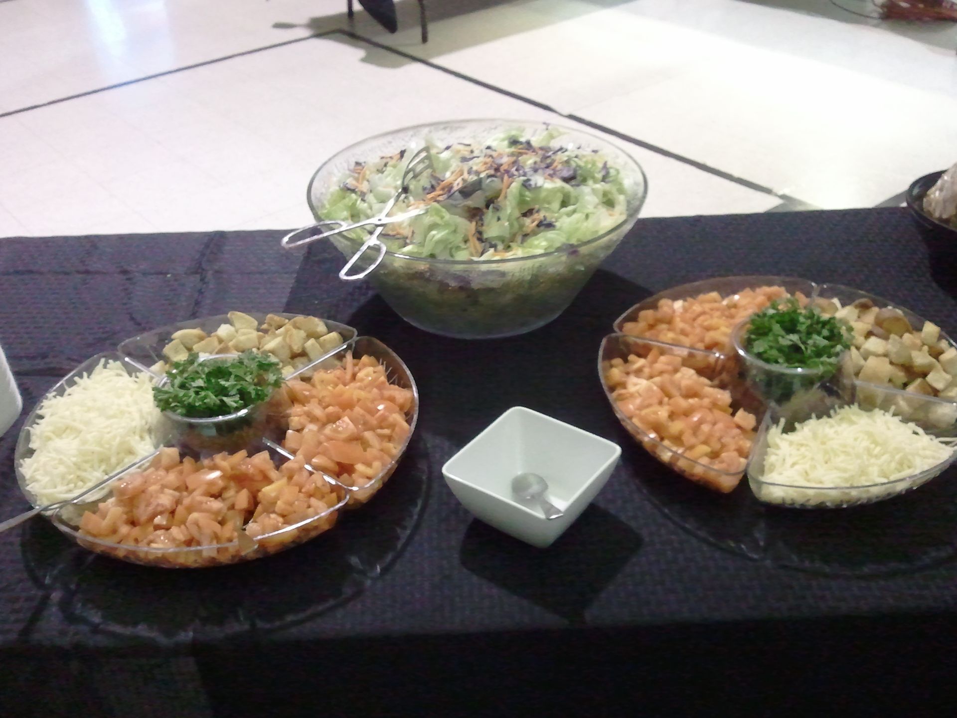 Two platters and a salad bowl on a table, with rice, salmon, and vegetables in a buffet-style meal.