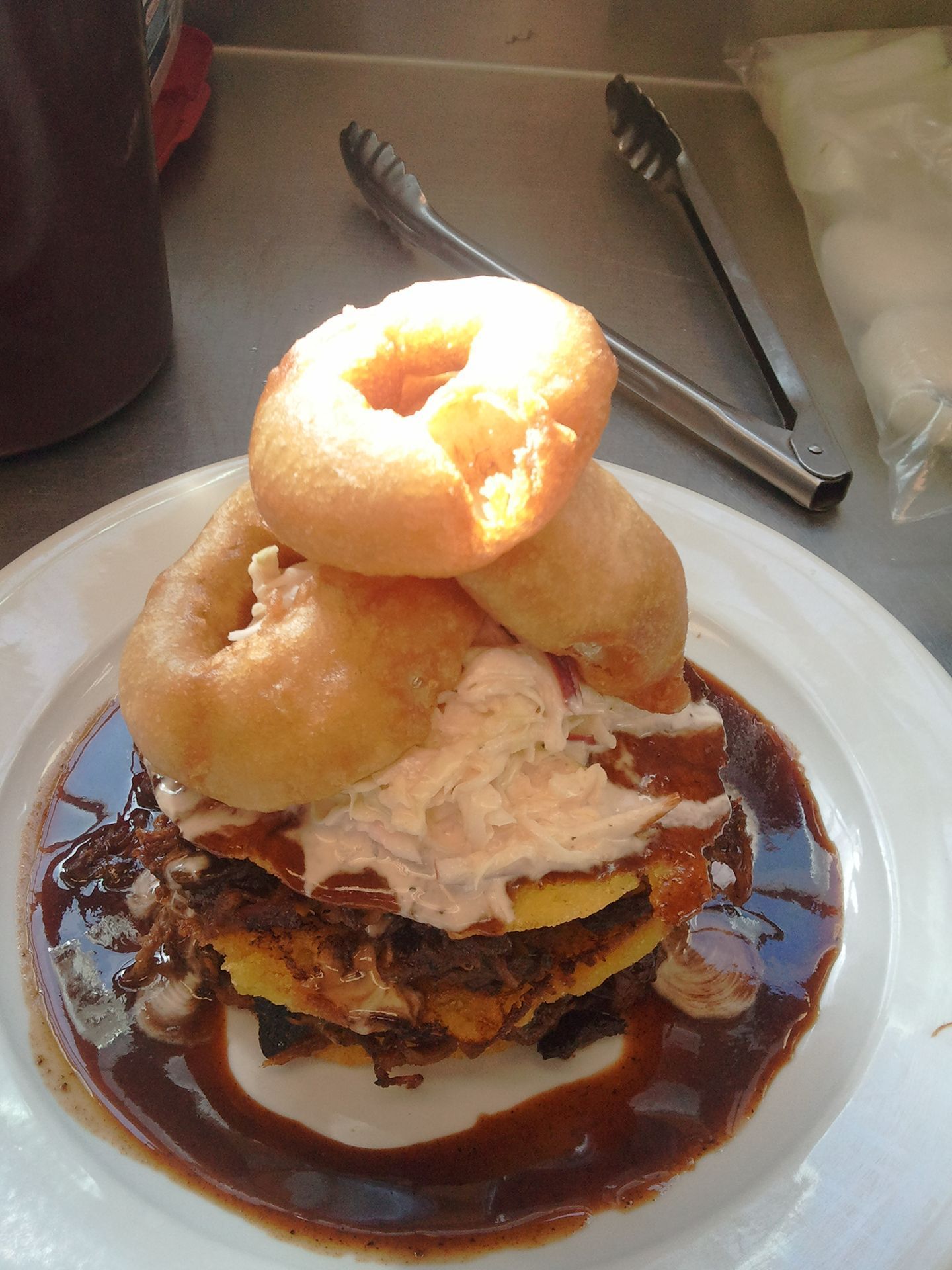 Stacked dessert with donuts, whipped cream, and ice cream on a plate drizzled with chocolate sauce