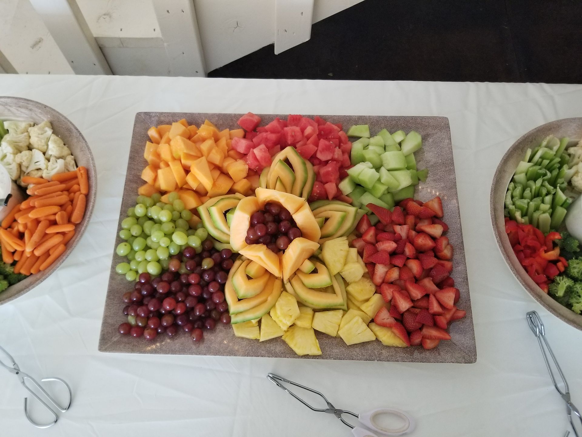 Fruit and veggie tray with assorted chopped produce arranged in sections on a table