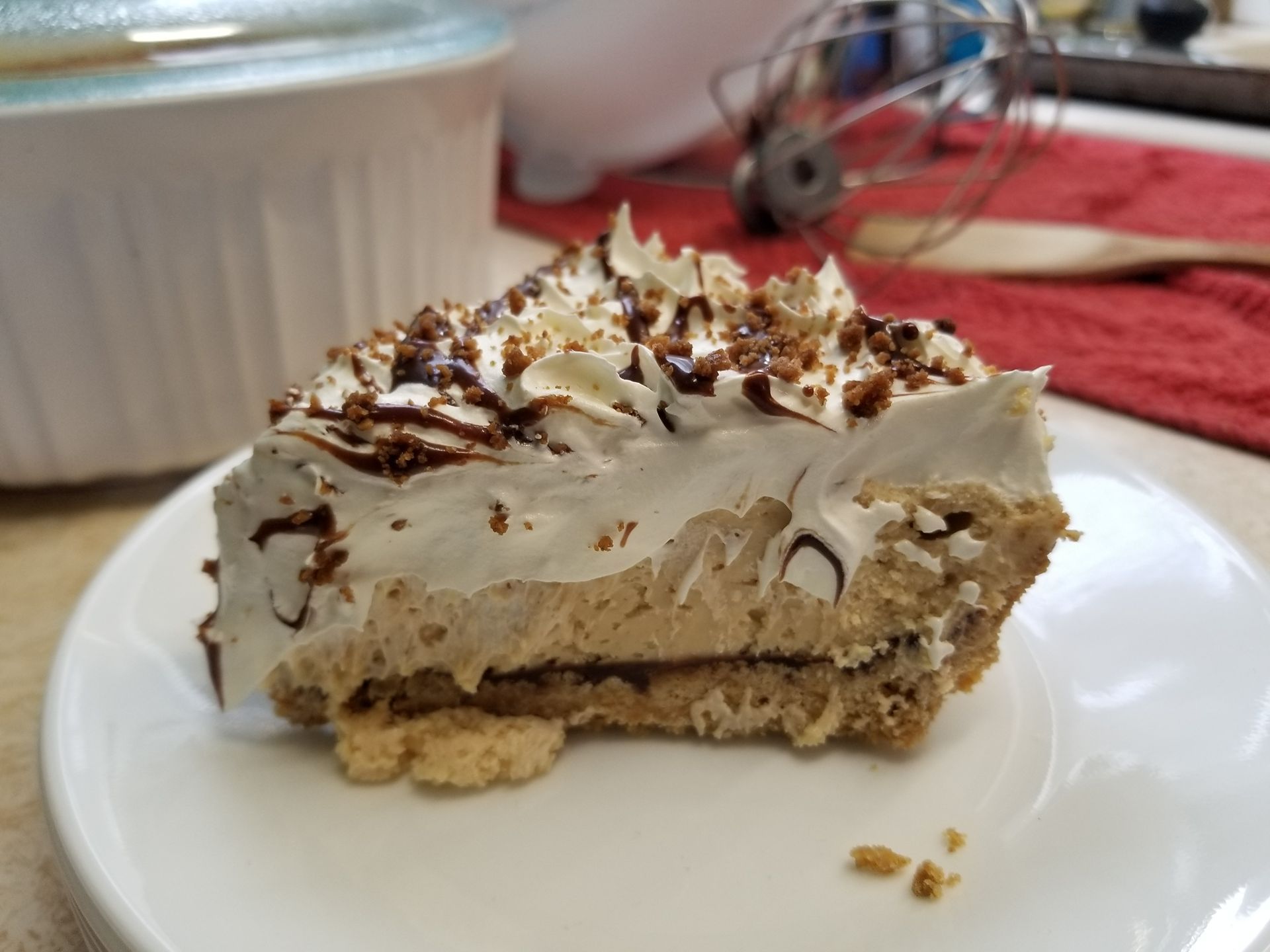 Slice of layered dessert with whipped cream and chocolate shavings on a white plate