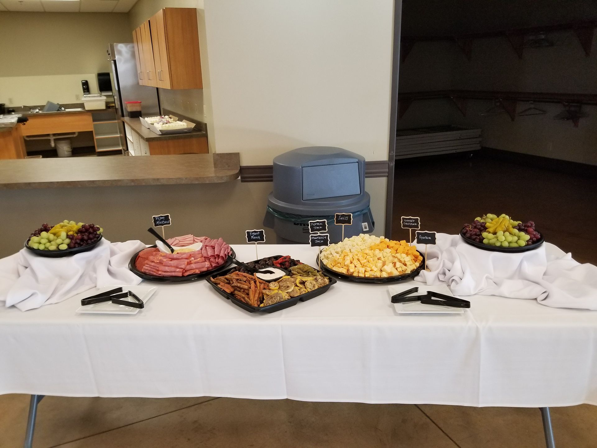 Buffet table with appetizers, fruit bowls, and serving utensils in a dining room