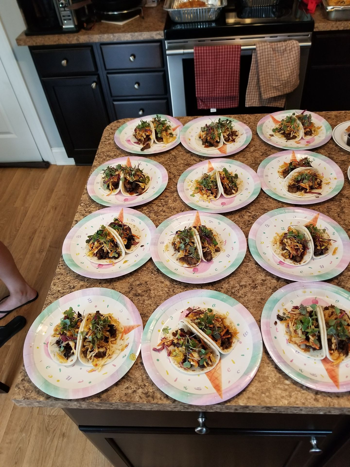 Twelve plated tacos arranged on a kitchen counter, ready to serve.