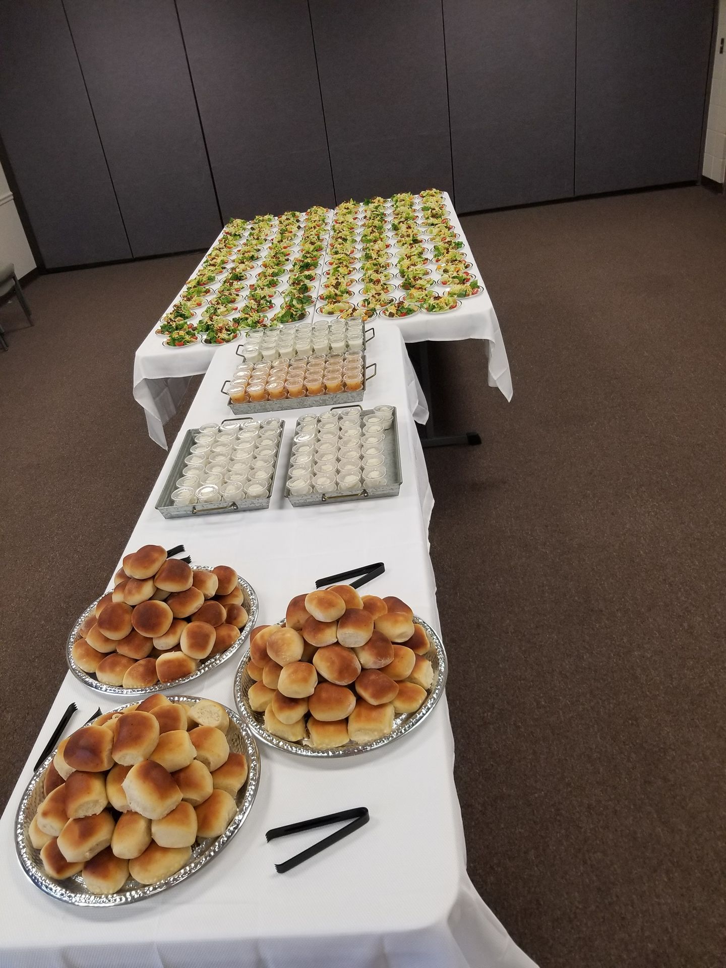 Buffet table with trays of pastries and dessert cups in a conference room