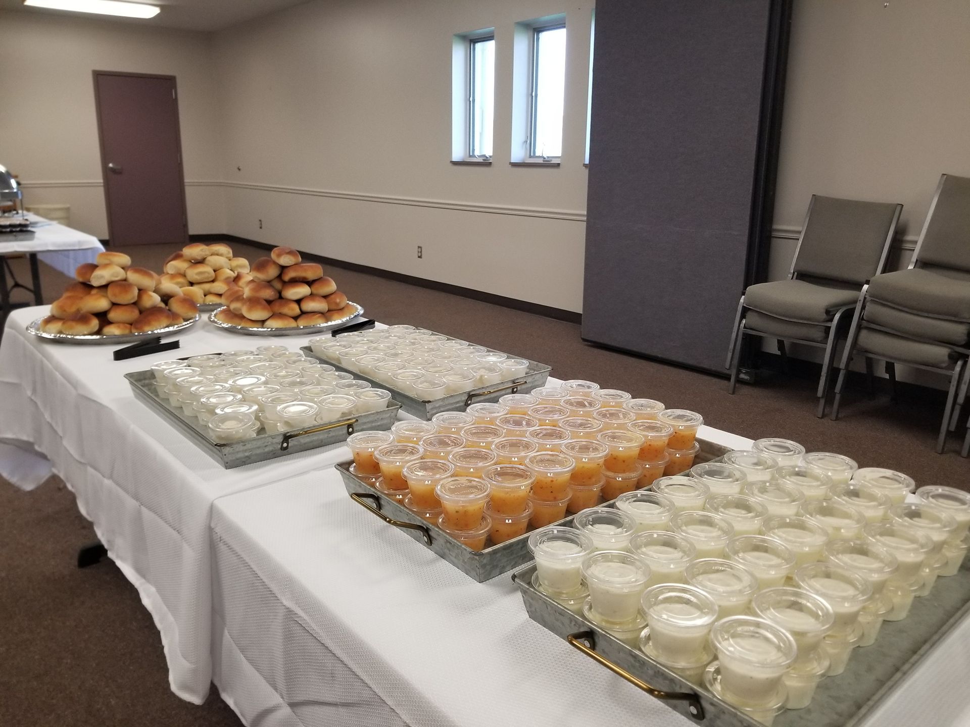 Refreshment table with pastries and dessert cups in a room with chairs along the wall