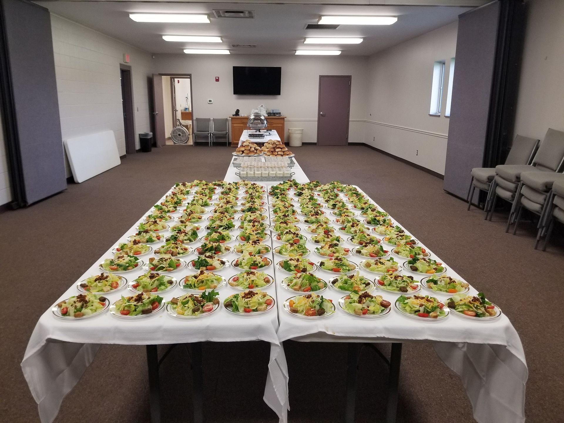 Long banquet tables with plated salads in a meeting room, ready for an event