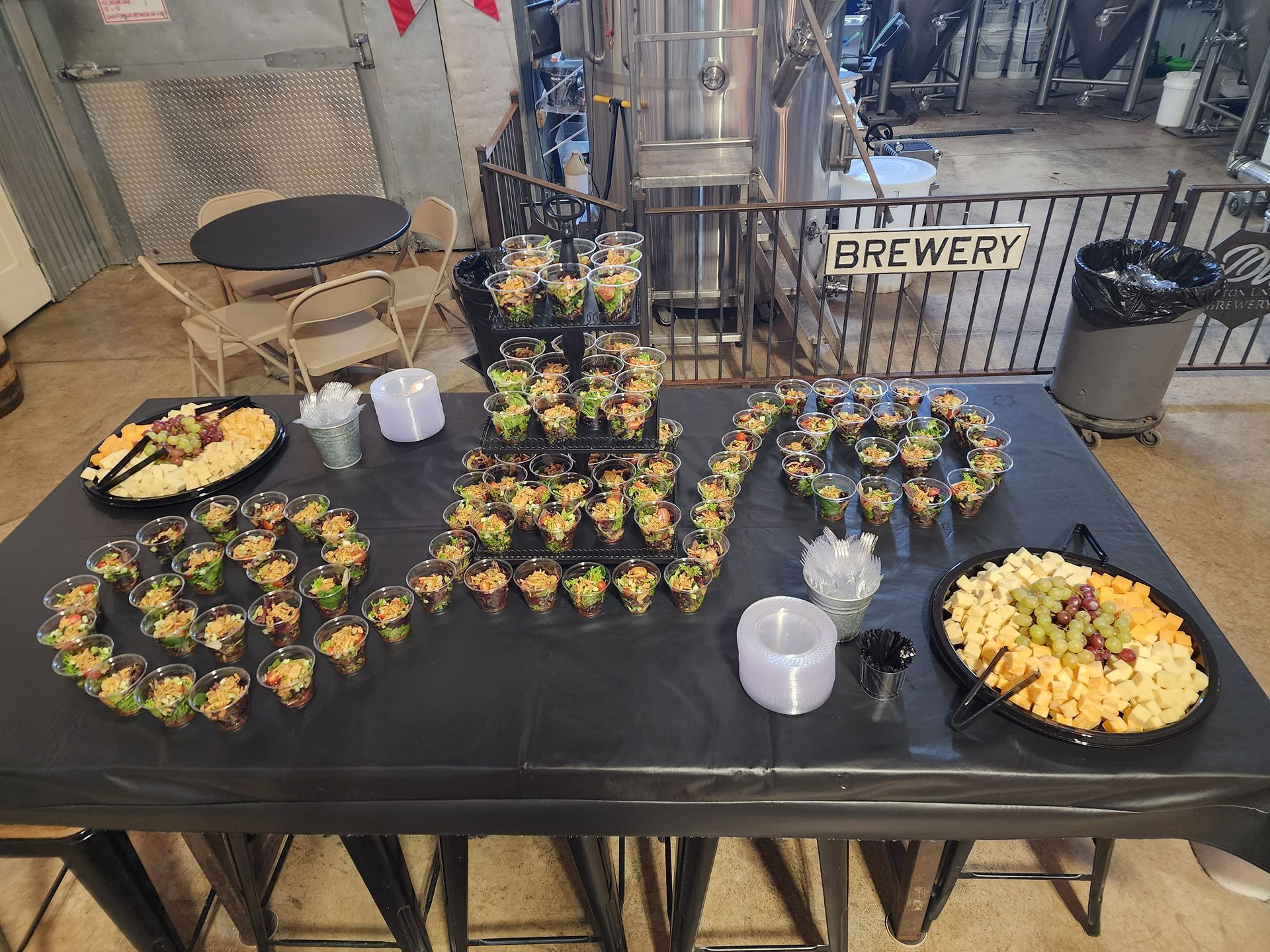 Round appetizer platters on a black table at a brewery event, with a “BREWERY” sign in back.