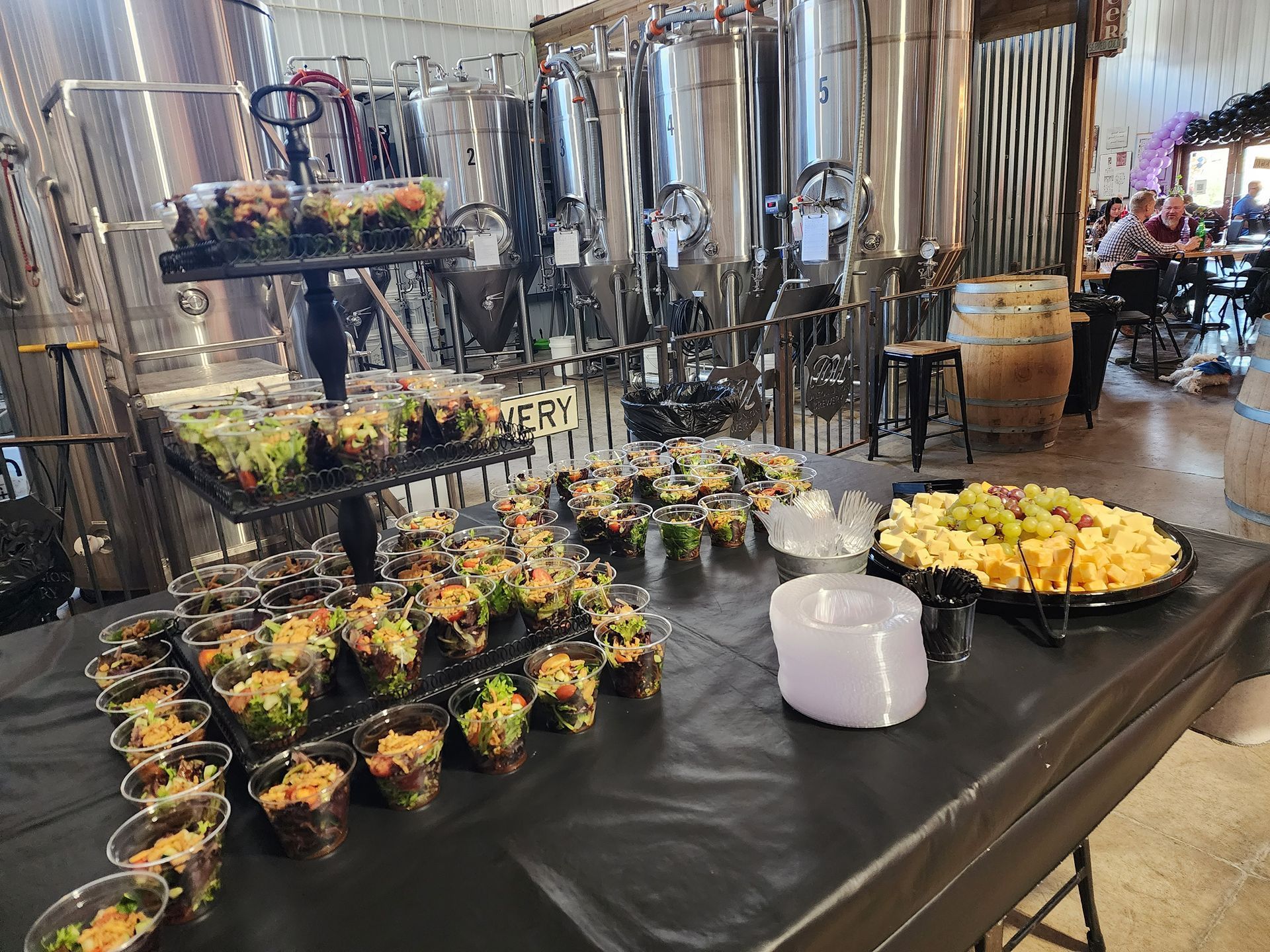 Buffet table with rows of small salad cups and yellow-topped appetizers at a catered event