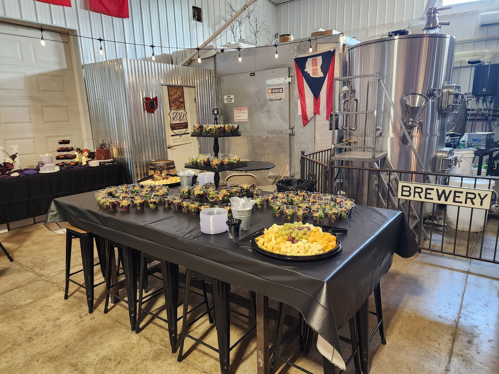 Buffet table with fruit, pastries, and drinks at a brewery event indoors