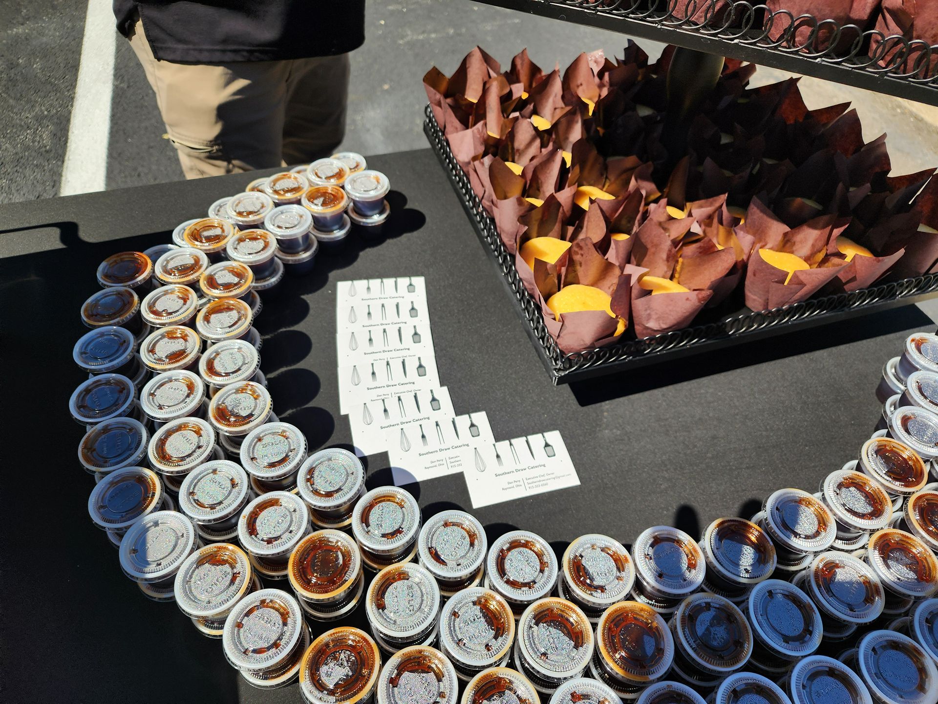 Table with many small dessert cups and folded napkins at an outdoor event