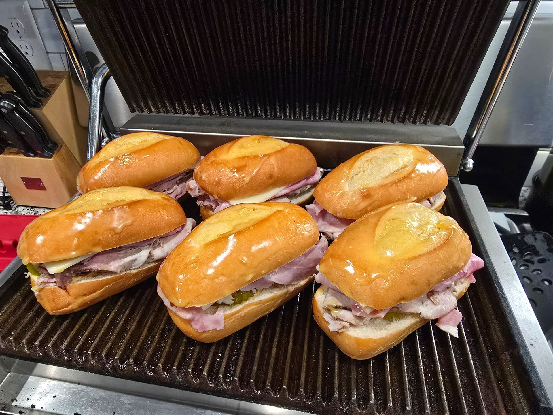 Six toasted sandwich rolls with fillings on a ridged grill or panini press