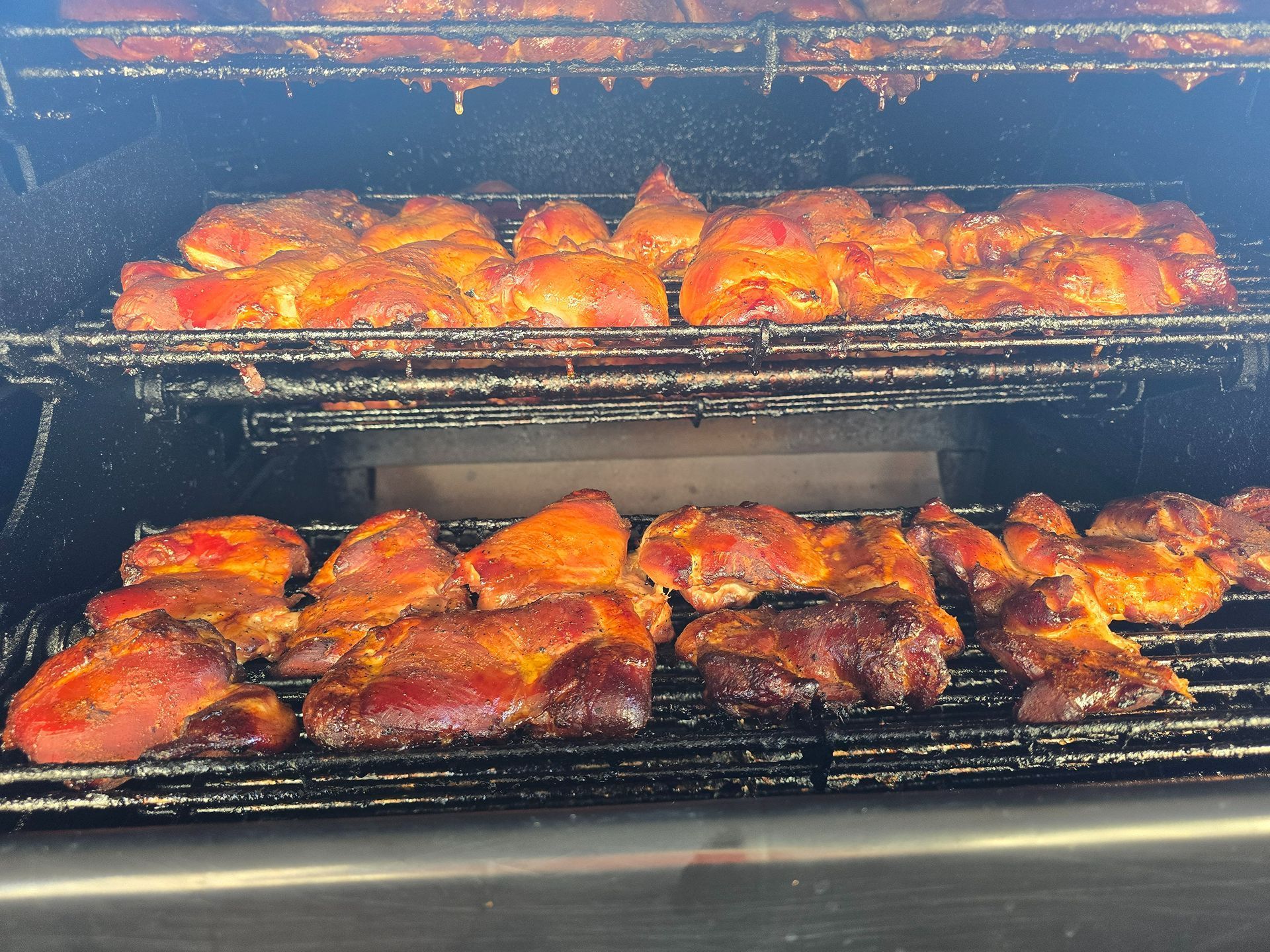 Chicken wings grilling on two barbecue racks, browned and glazed over open heat.