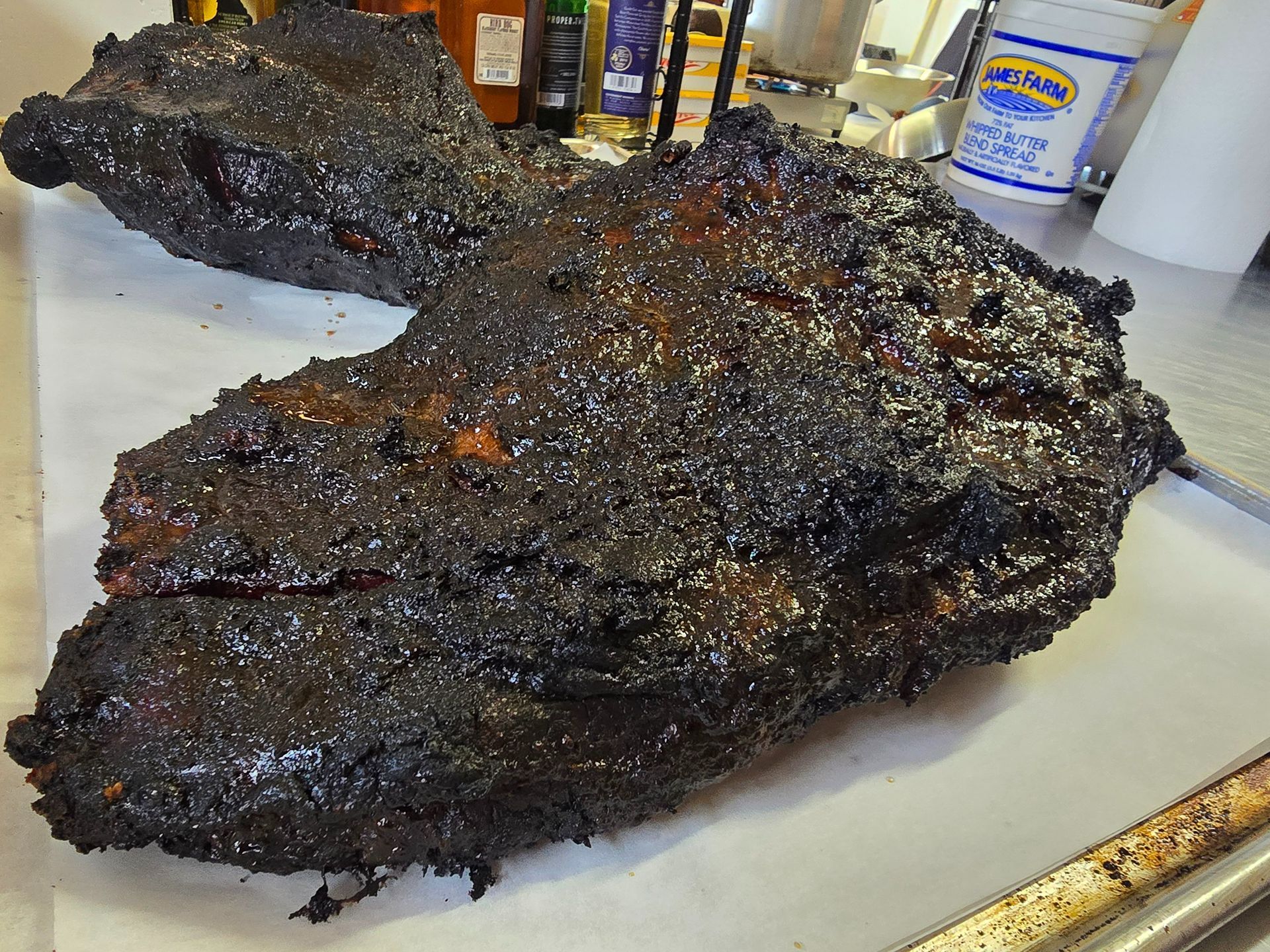 Two large pieces of blackened smoked meat on a countertop